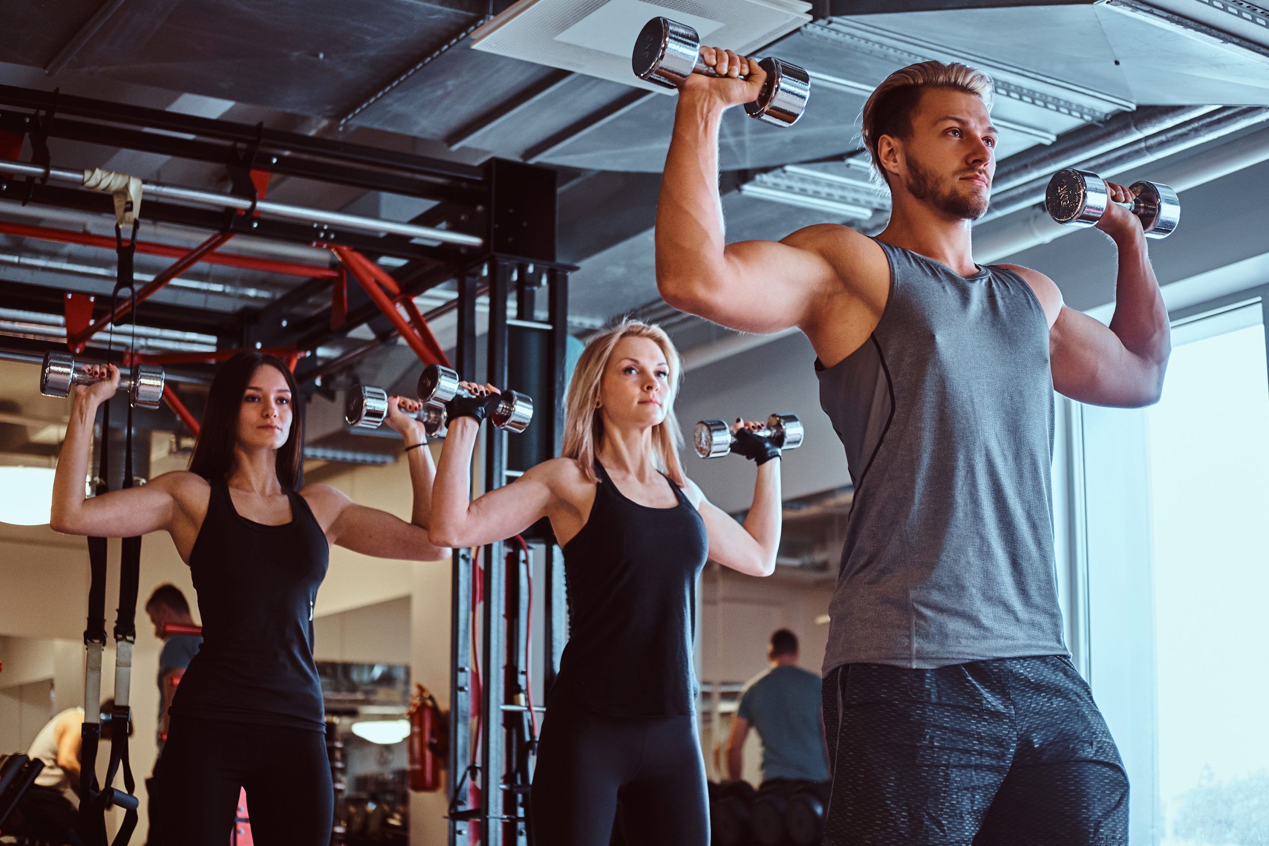 Group of people exercising with dumbbells in the fitness club or gym.